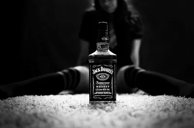 Обои на рабочий стол Бутылка виски Джек Дениэлс / Jack Daniels позади  которой сидит девушка в гольфах, обои для рабочего стола, скачать обои,  обои бесплатно