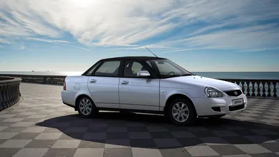 VAZ Lada Priora white stands on the road near a beautiful building -  wallpapers for your phone