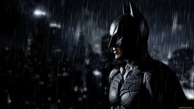 Обои на рабочий стол Бэтмен стоит под сильным дождём на фоне небоскрёбов  Готэм-сити, обои для рабочего стола, скачать обои, обои бесплатно